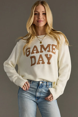 Woman wearing a 'GAME DAY' sweater and jeans against a gray background
